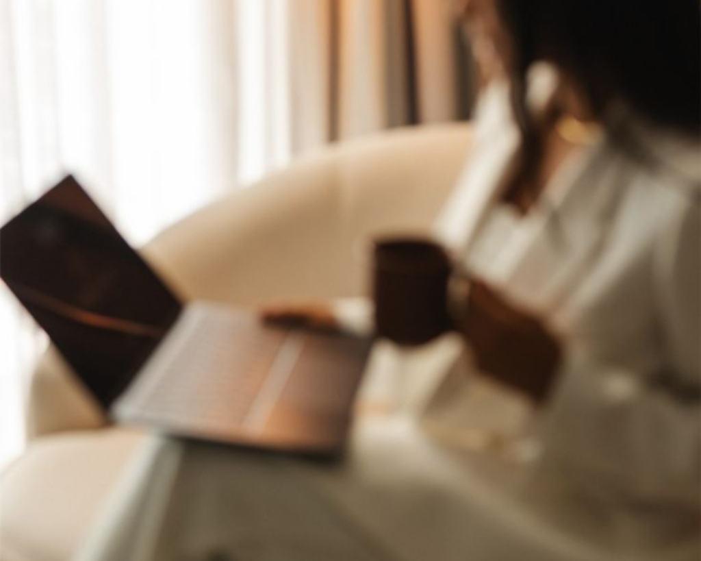 Woman sitting on a sofa with a laptop on her lap looking at a Logo Brand Design That Converts & Elevates
